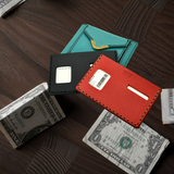 Three cardholders in black, red, and teal on a wooden surface with dollar bills.