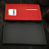Red and black leather card holders on a dark surface
