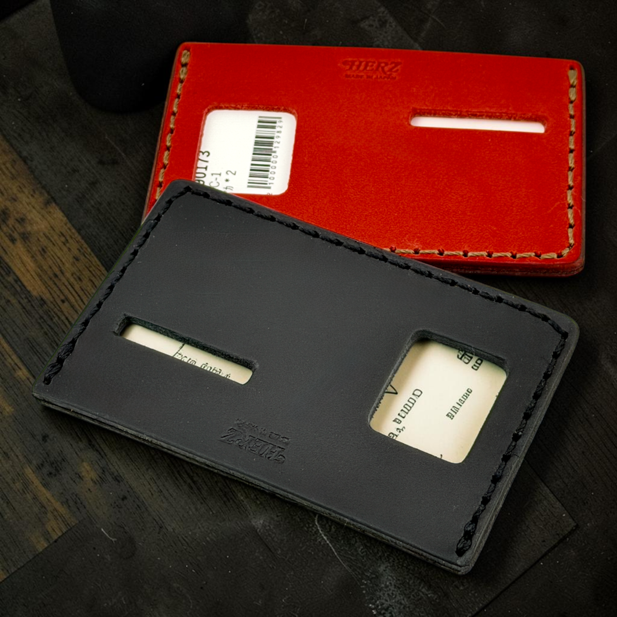 Black and red leather card holders on a dark wooden surface