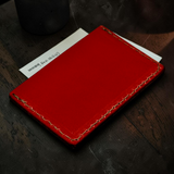 Red leather cardholder on a dark wooden surface