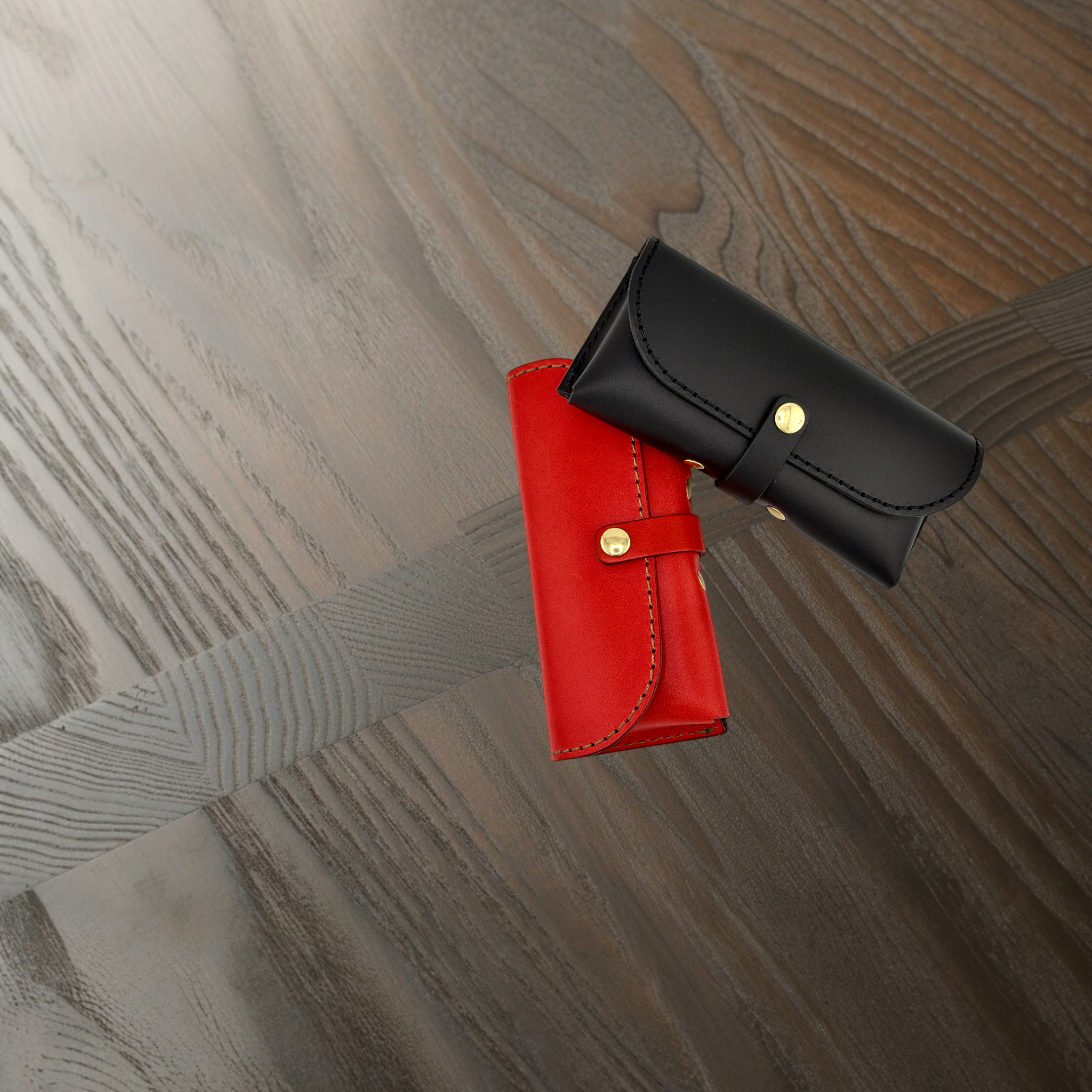 Red and black leather eyewear cases on a wooden surface