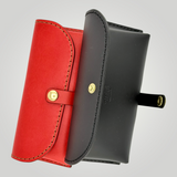 Red and black leather eyewear cases with gold accents on a gray background