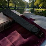 Coffee cup on a book with a belt and wallet in the foreground, set against a park background.
