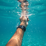 Hand with a watch underwater in clear blue water