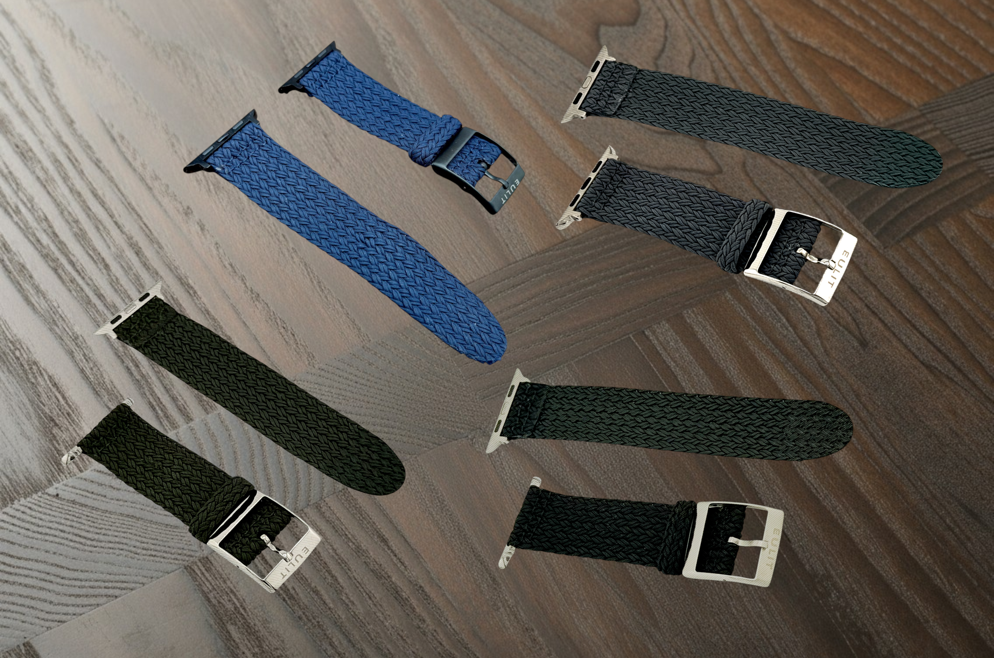 Set of watch straps in blue, black, and silver on a wooden surface